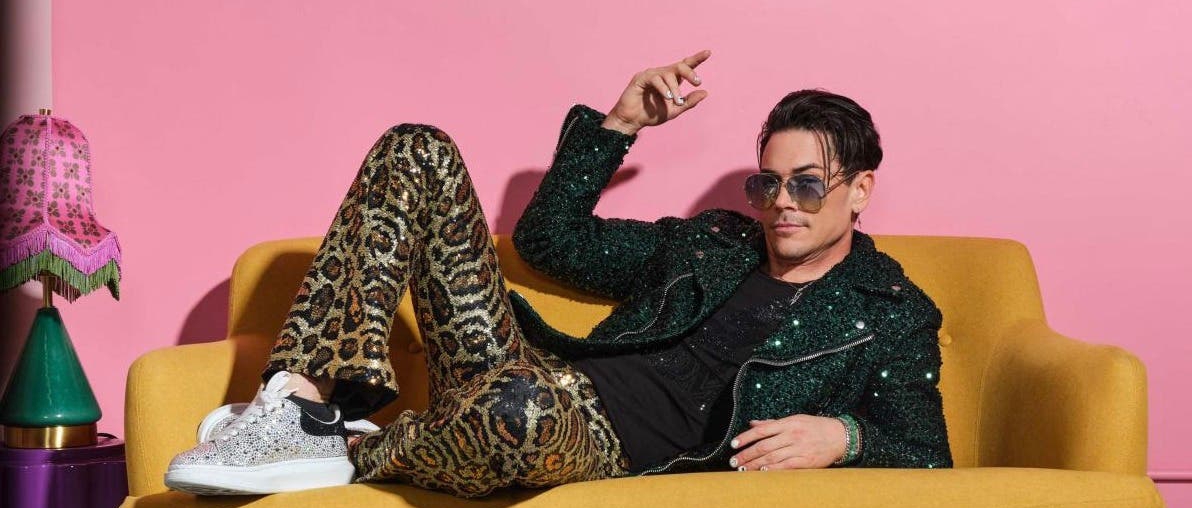 Tom Sandoval on a yellow couch in front of a pink background