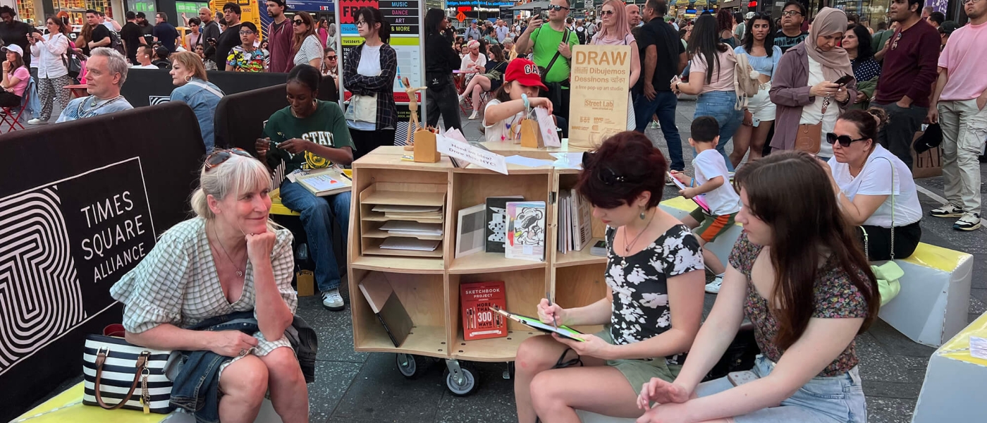 A group of people sitting and drawing at a Street Lab pop up in Times Square